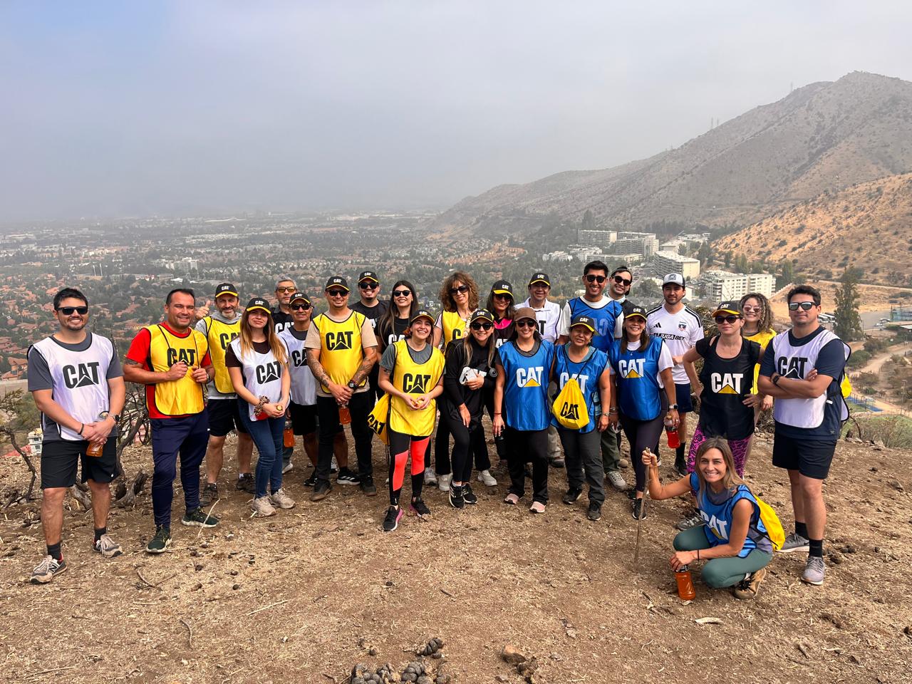 Grupo corporativo en trekking por los cerros de Huechuraba con vista panorámica de Santiago